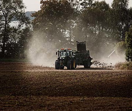 En traktor sprider ut gödsel på ett fält.